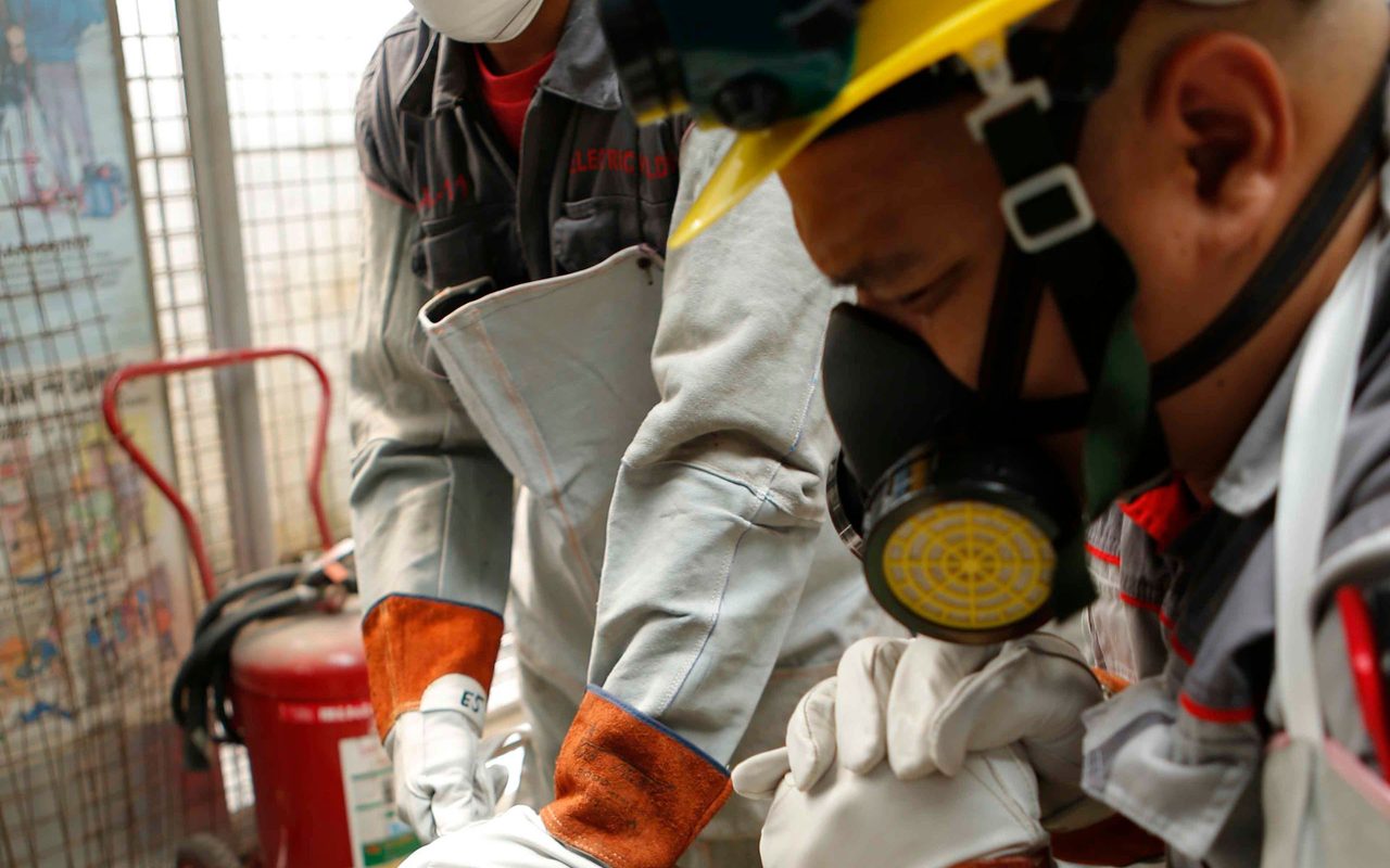 Two workers in safety gear cutting metal in a workshop in the Philippines