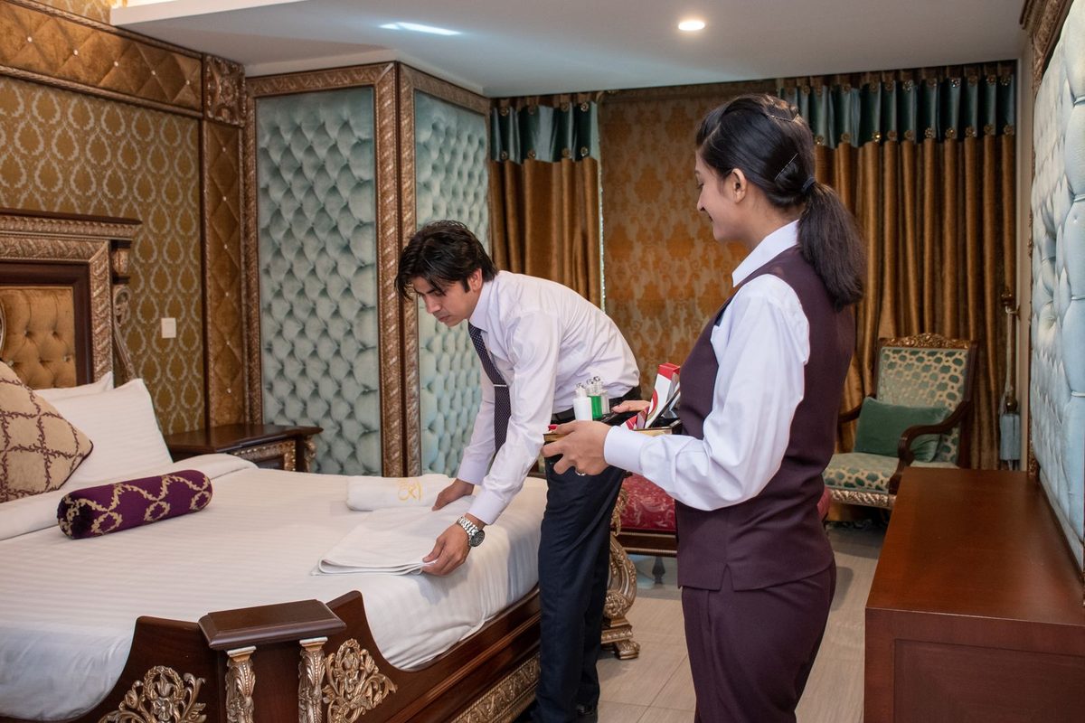 Two hotel staff preparing a guest room